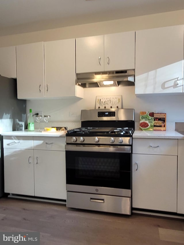 kitchen featuring under cabinet range hood, white cabinets, gas stove, and light countertops