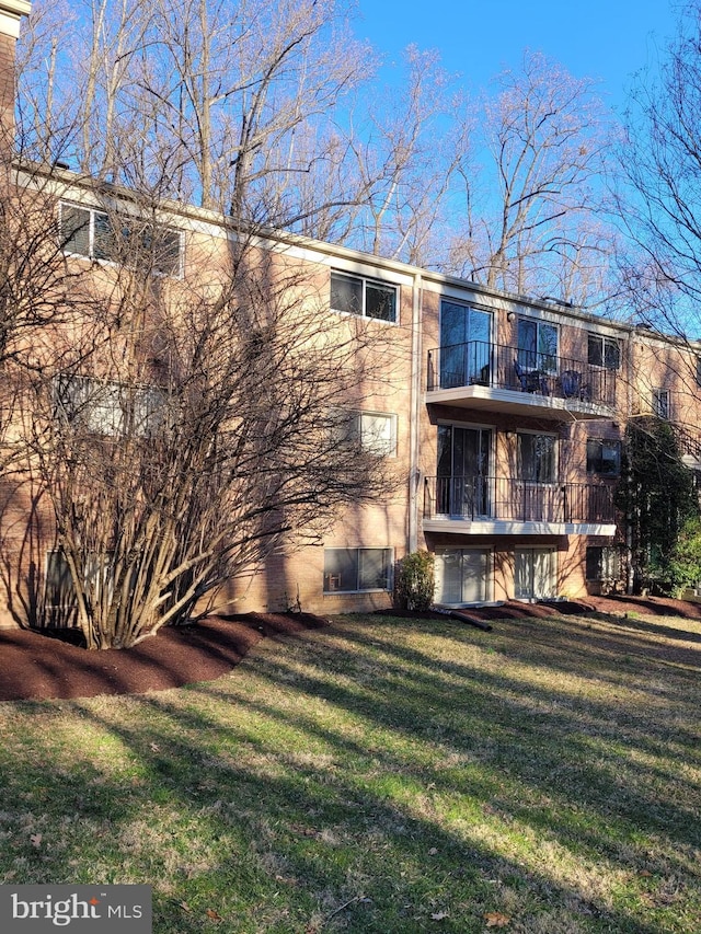 back of property with a balcony and a lawn