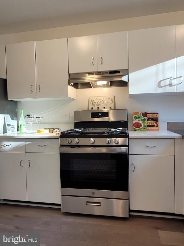 kitchen featuring under cabinet range hood, white cabinets, gas stove, and light countertops