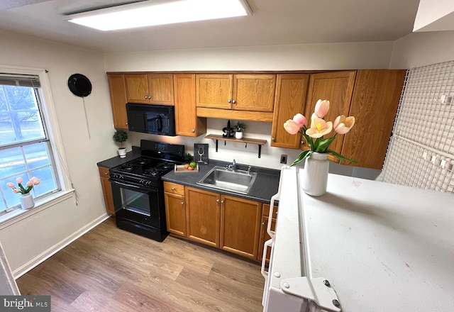 kitchen featuring brown cabinetry, black appliances, dark countertops, and a sink