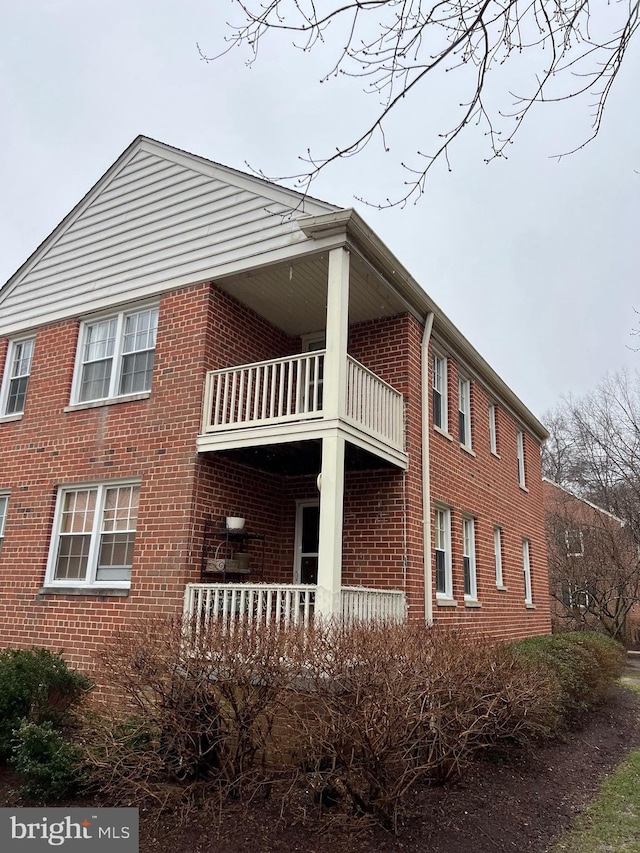 view of property exterior featuring a balcony and brick siding