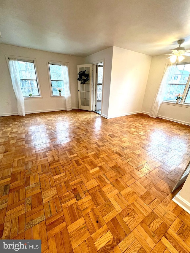 spare room featuring a healthy amount of sunlight, baseboards, and ceiling fan