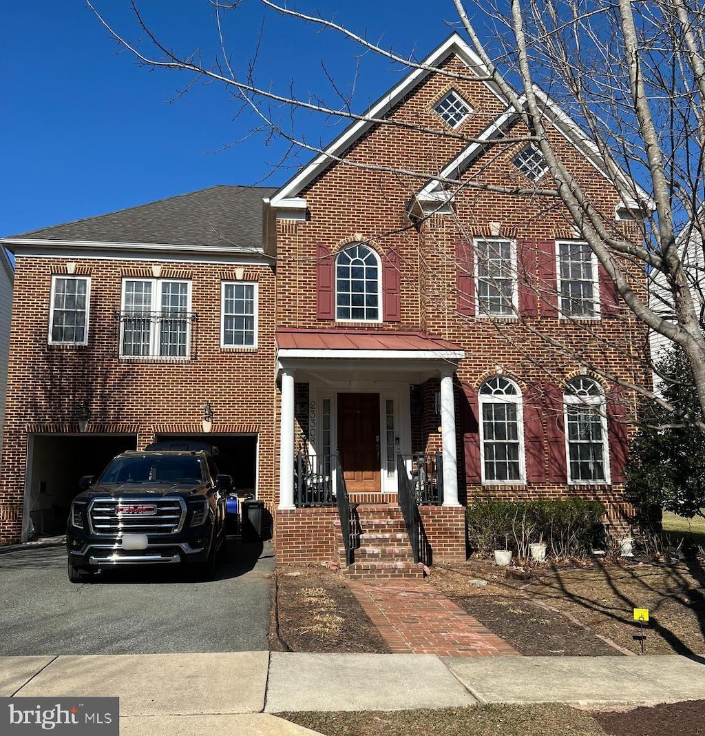 view of front of property with brick siding, driveway, an attached garage, and roof with shingles