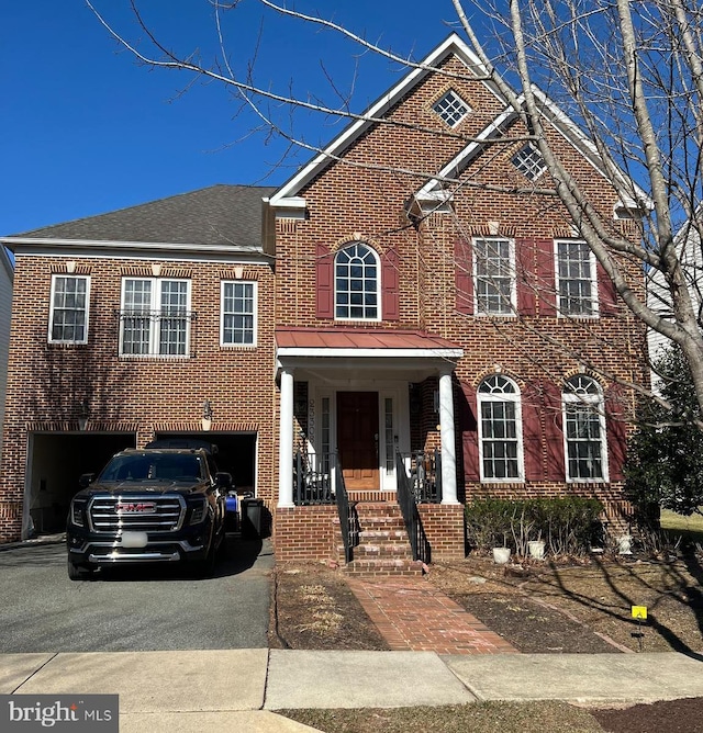 view of front of property with brick siding, driveway, an attached garage, and roof with shingles