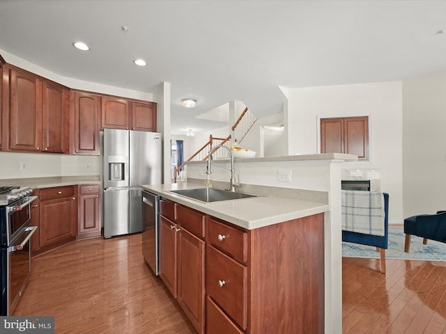 kitchen with a sink, appliances with stainless steel finishes, light wood-style flooring, and light countertops