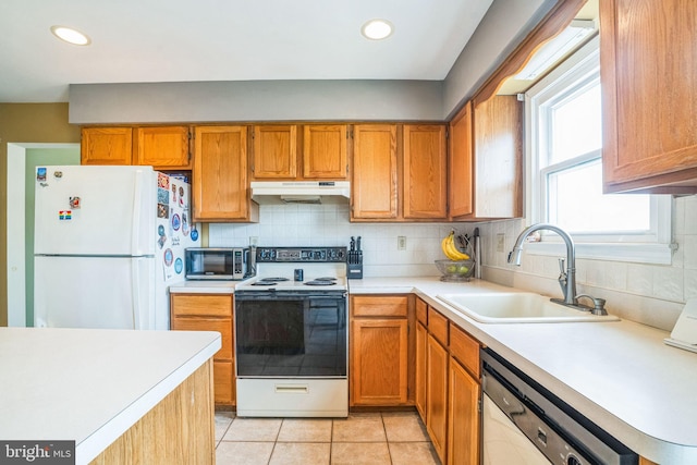 kitchen with electric stove, under cabinet range hood, a sink, freestanding refrigerator, and dishwasher