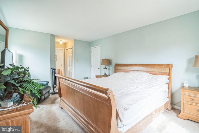 bedroom with light colored carpet and ensuite bathroom