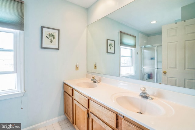 full bath with a sink, a stall shower, double vanity, and tile patterned flooring