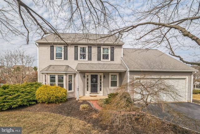 traditional home with aphalt driveway, a garage, and a shingled roof