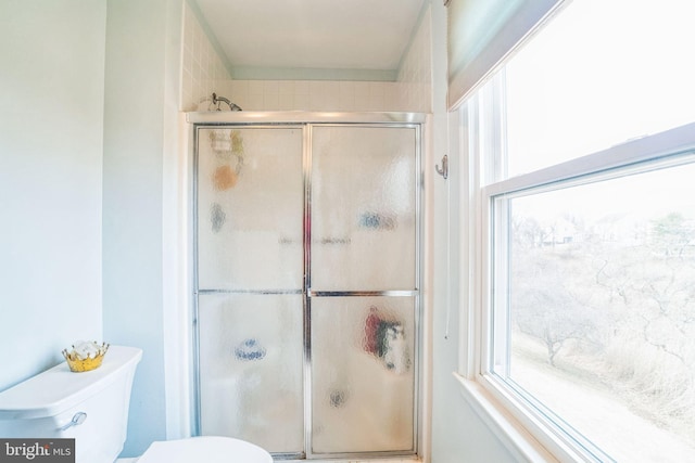 bathroom featuring toilet and shower / bath combination with glass door