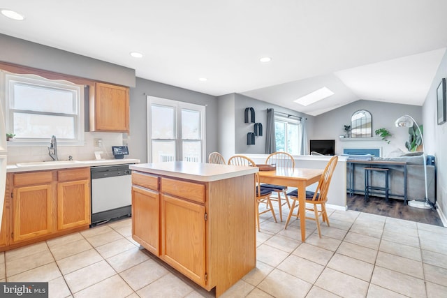 kitchen featuring lofted ceiling with skylight, a sink, a center island, light tile patterned flooring, and dishwasher