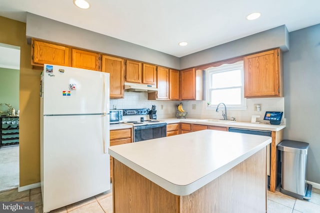 kitchen featuring white appliances, a sink, decorative backsplash, light countertops, and under cabinet range hood