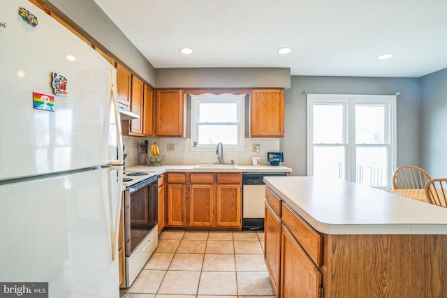 kitchen with white appliances, light tile patterned flooring, a sink, light countertops, and brown cabinets