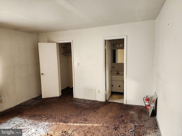 unfurnished bedroom featuring ensuite bath, carpet floors, and a sink