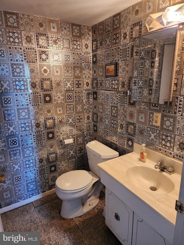 bathroom featuring tile patterned floors, toilet, vanity, and tile walls