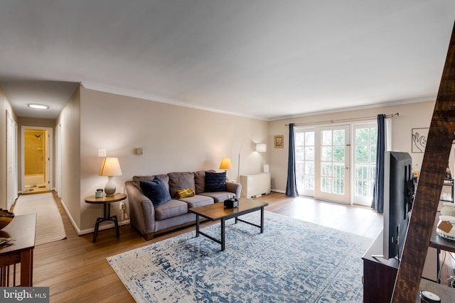 living room with light wood-type flooring, baseboards, and crown molding