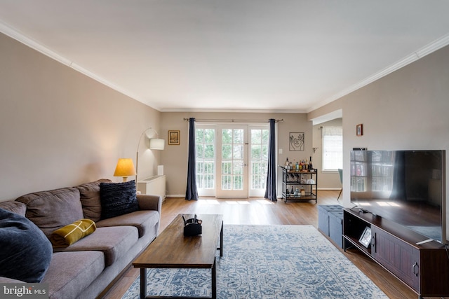 living area featuring baseboards, wood finished floors, and crown molding