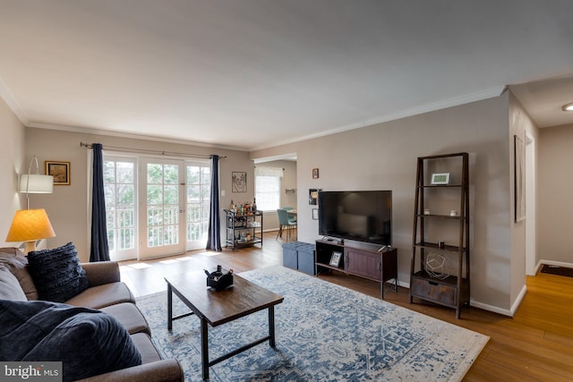 living area featuring crown molding, wood finished floors, and baseboards