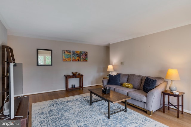 living room featuring crown molding, baseboards, and wood finished floors