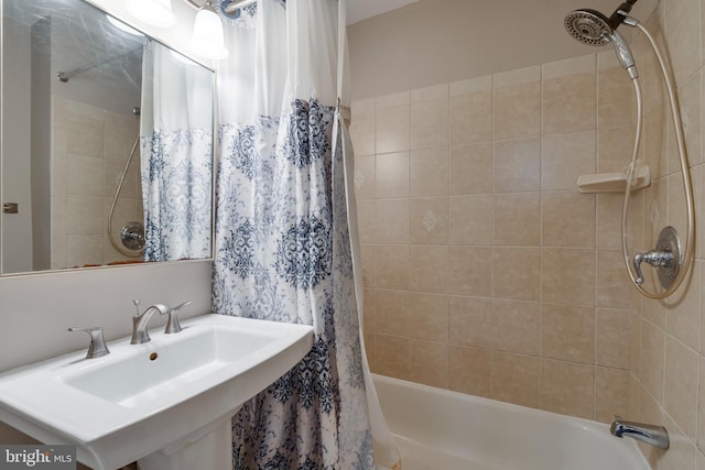 bathroom with shower / bath combination with curtain and a sink