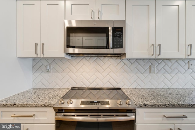 kitchen with stainless steel appliances, light stone countertops, decorative backsplash, and white cabinetry