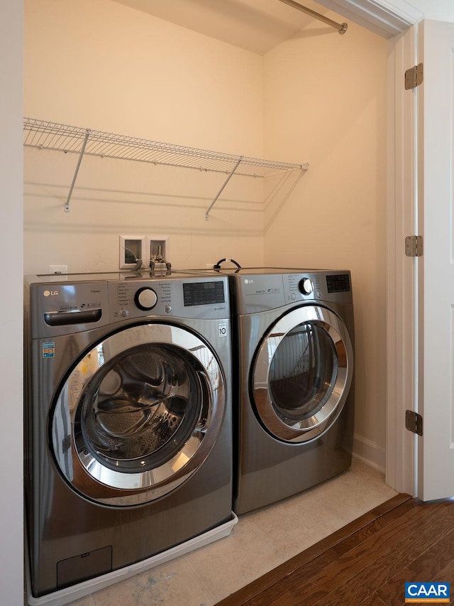 clothes washing area with wood finished floors, washing machine and dryer, and laundry area