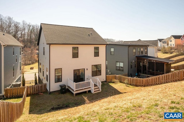 back of house featuring a deck, fence, a yard, cooling unit, and a shingled roof