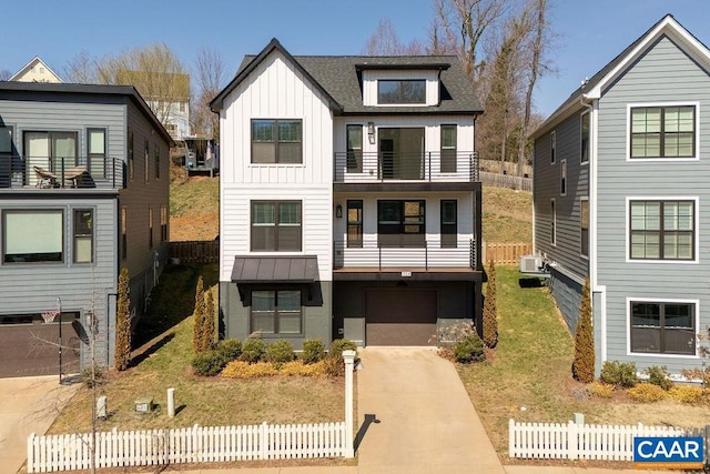 view of front facade featuring a front yard, a balcony, fence, concrete driveway, and board and batten siding