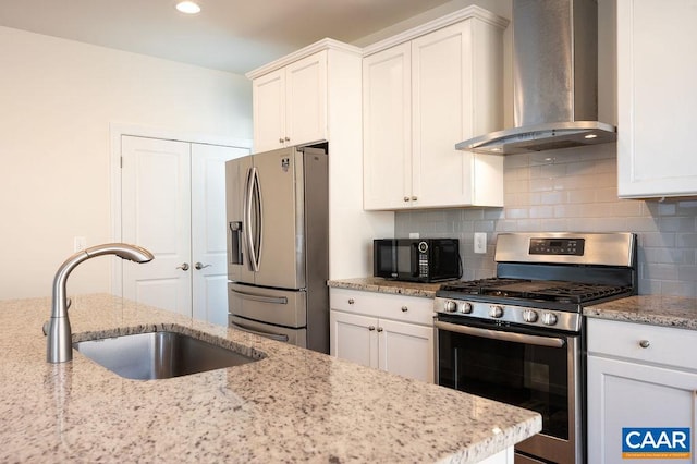 kitchen with a sink, appliances with stainless steel finishes, white cabinetry, wall chimney exhaust hood, and backsplash