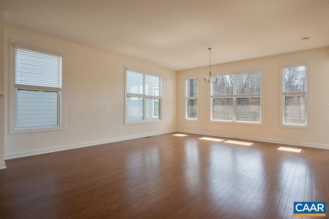 interior space with a notable chandelier, dark wood-type flooring, and baseboards