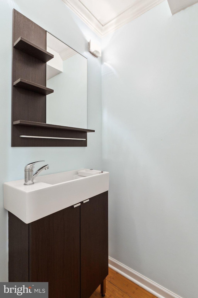 bathroom with baseboards, vanity, wood finished floors, and crown molding