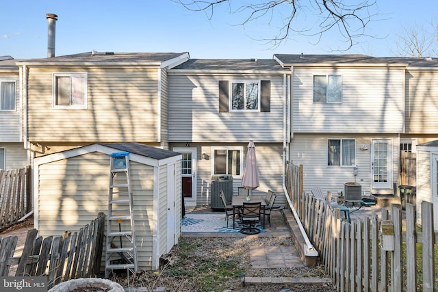 rear view of property featuring a patio, an outbuilding, a fenced backyard, and a shed