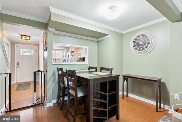 dining space with baseboards, wood finished floors, and ornamental molding