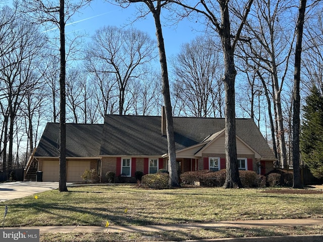 view of front of house with brick siding, a front lawn, roof with shingles, driveway, and an attached garage