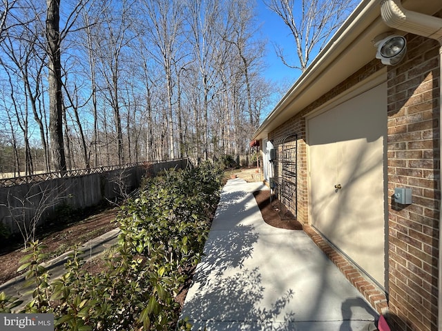 view of side of property featuring brick siding and fence