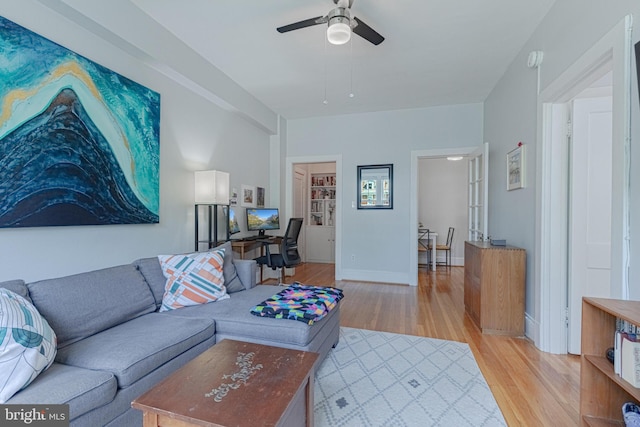 living area featuring light wood-style flooring, a ceiling fan, and baseboards