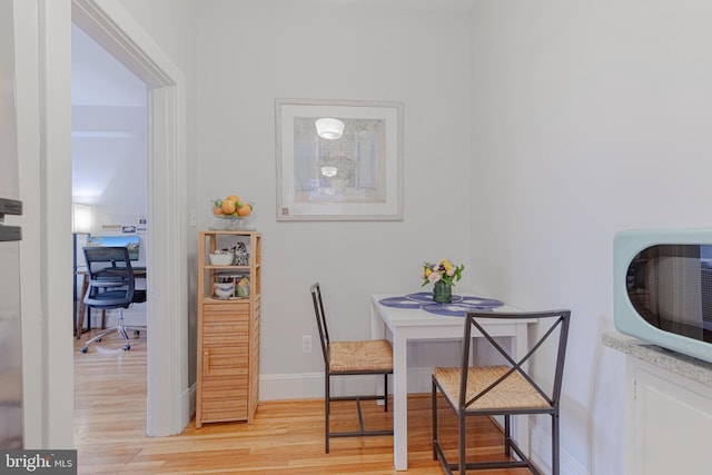 dining space featuring baseboards and light wood-style flooring