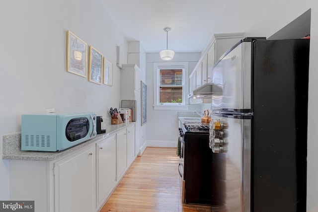 kitchen with white cabinetry, stainless steel appliances, light wood-style floors, light countertops, and baseboards