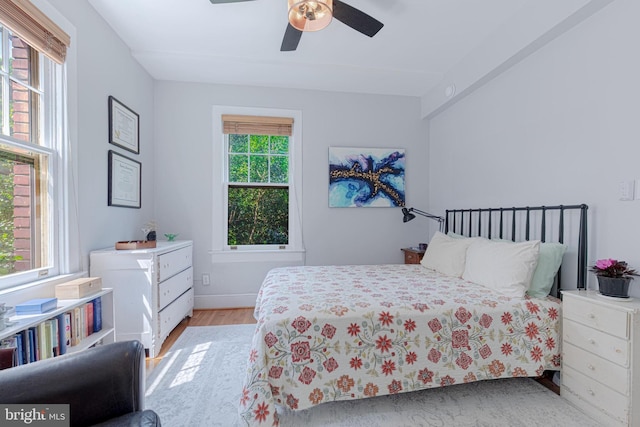 bedroom with a ceiling fan, light wood-type flooring, and baseboards