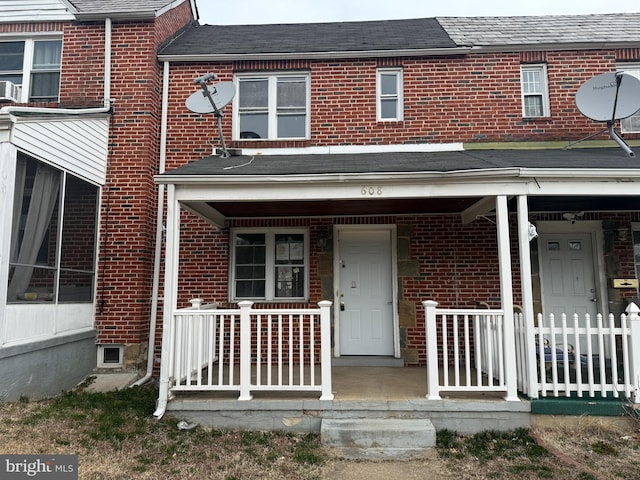 view of front of property with brick siding, covered porch, and roof with shingles