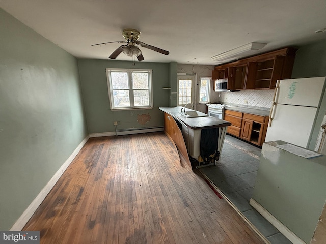 kitchen with baseboard heating, decorative backsplash, dark wood-style floors, white appliances, and a sink