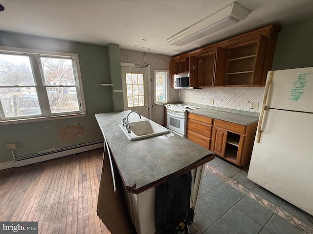 kitchen featuring a sink, open shelves, a baseboard radiator, white appliances, and a kitchen island with sink