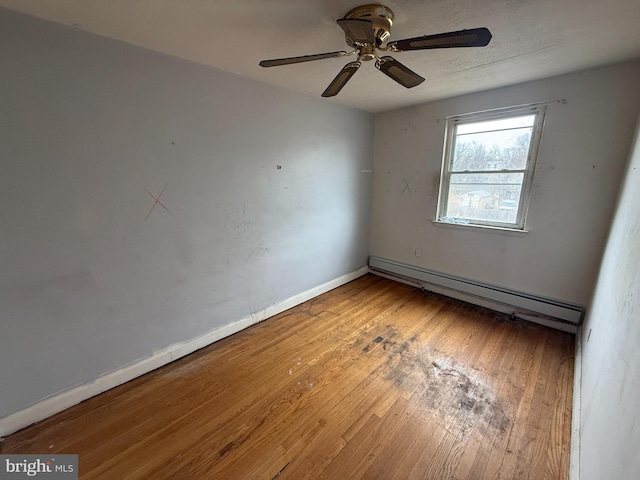 unfurnished room featuring hardwood / wood-style floors, a ceiling fan, baseboards, and a baseboard radiator