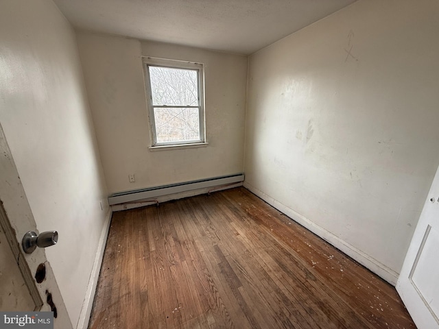 unfurnished room featuring hardwood / wood-style flooring and a baseboard radiator