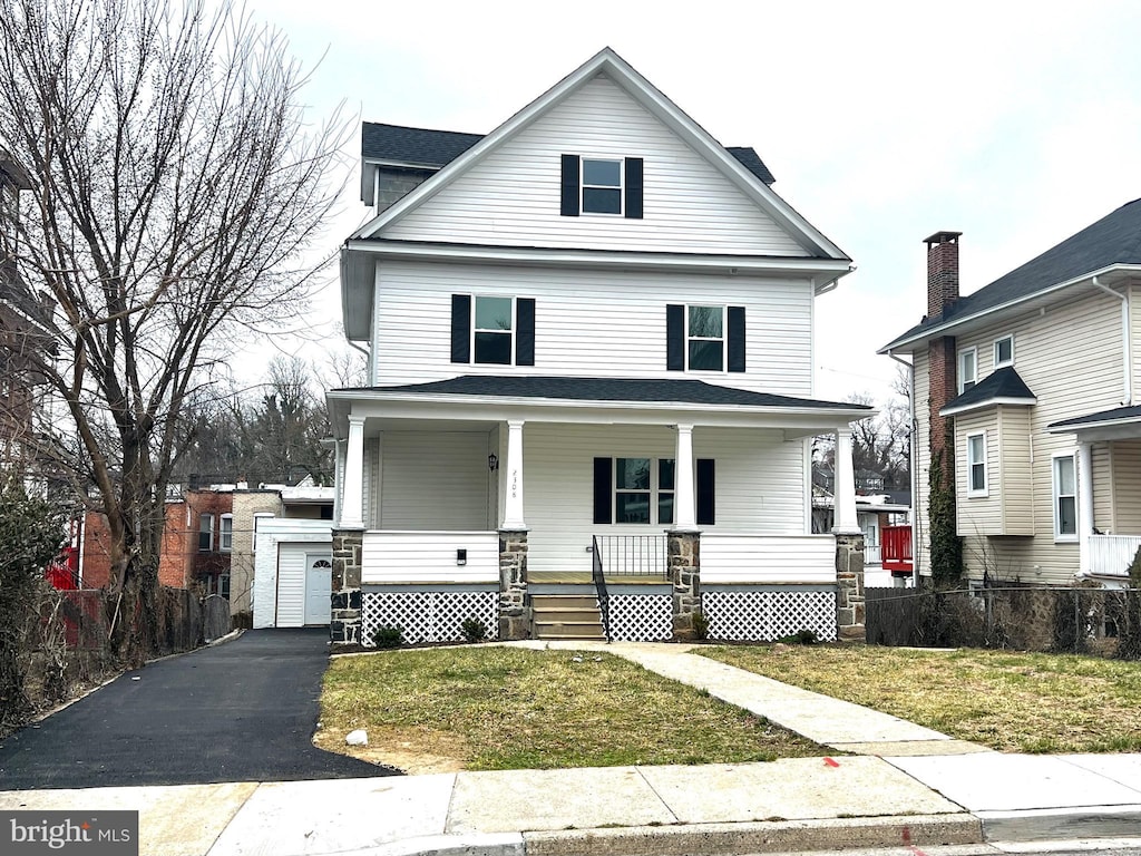 traditional style home with a front yard, fence, driveway, covered porch, and a garage