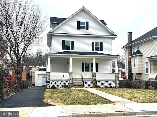 traditional style home with a front yard, fence, driveway, covered porch, and a garage