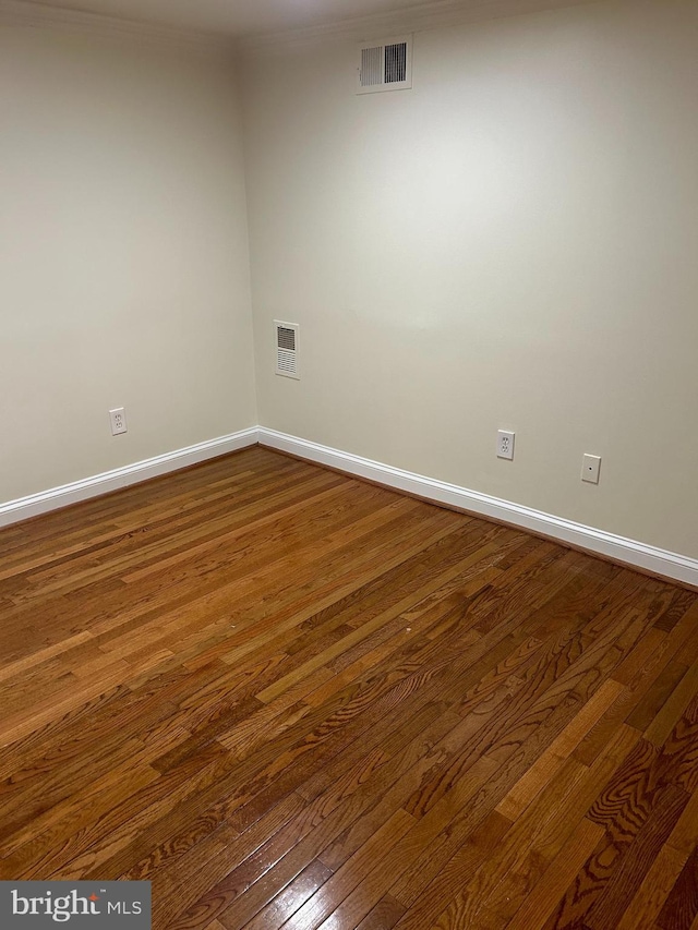 spare room featuring visible vents, baseboards, and dark wood-style floors