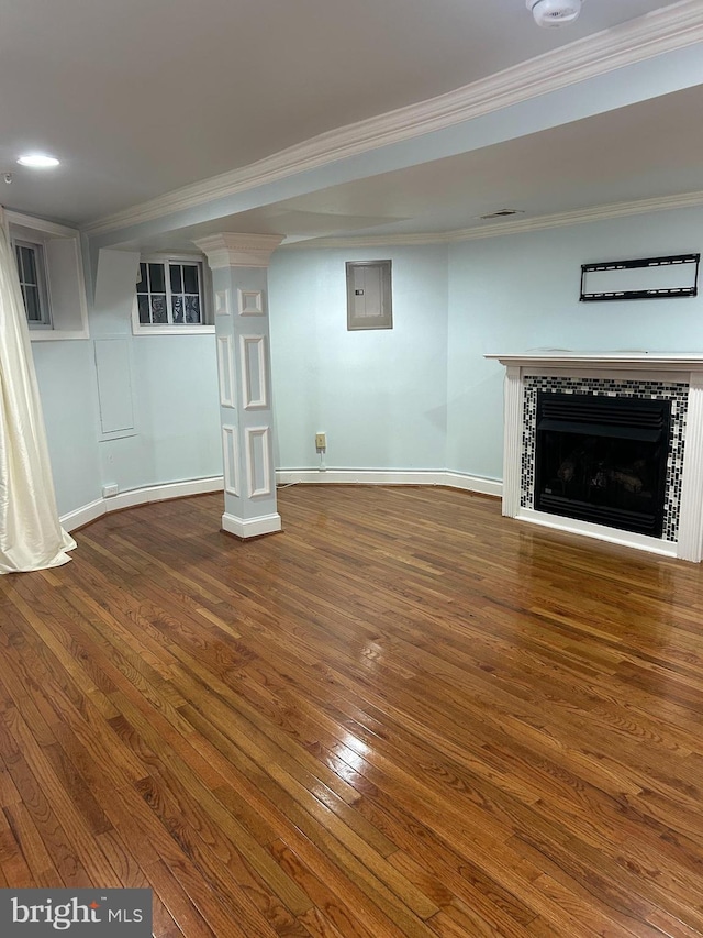 finished basement featuring baseboards, hardwood / wood-style floors, a fireplace, and ornamental molding