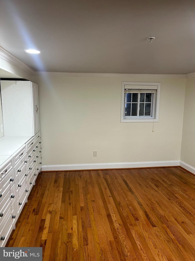 spare room with dark wood-style floors, baseboards, and ornamental molding