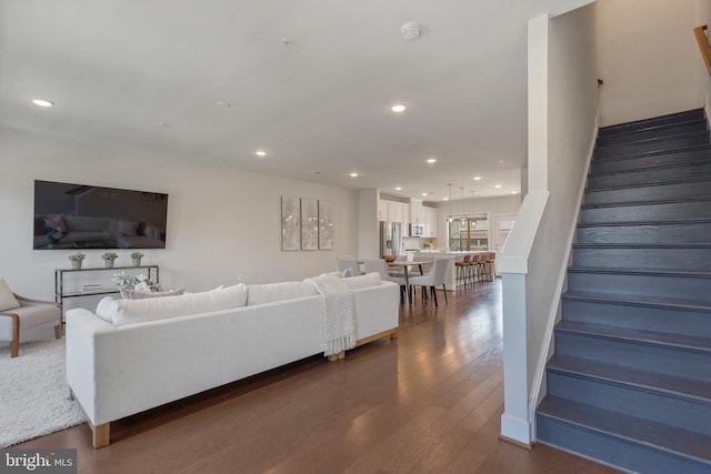 living room with stairway, recessed lighting, and dark wood-type flooring